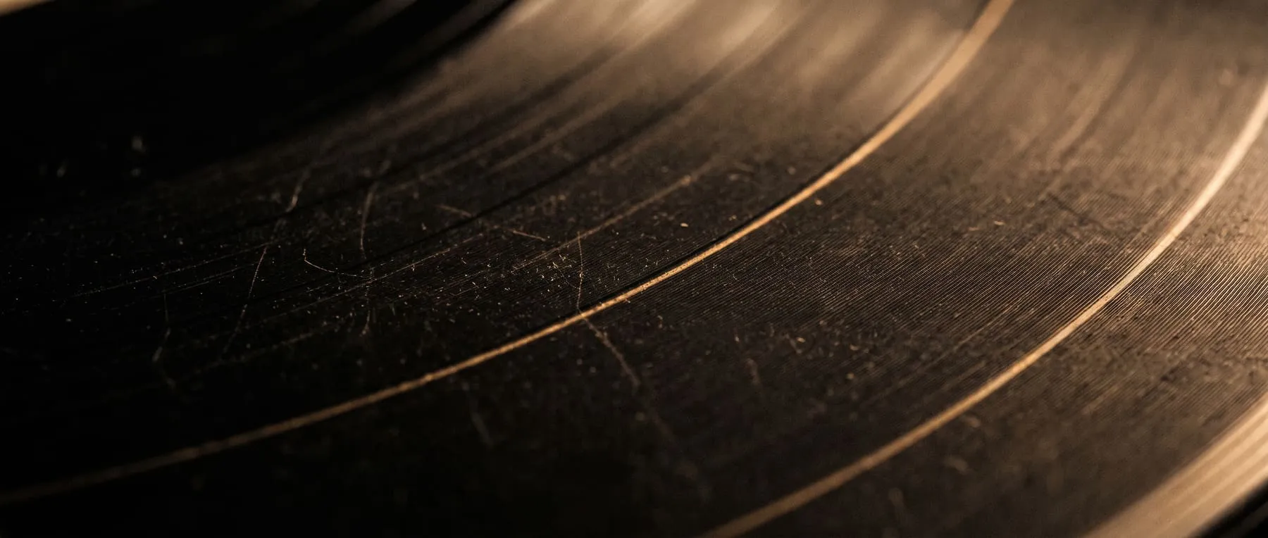 Ilustración: surco de un disco de vinilo gastado, iluminado a contraluz